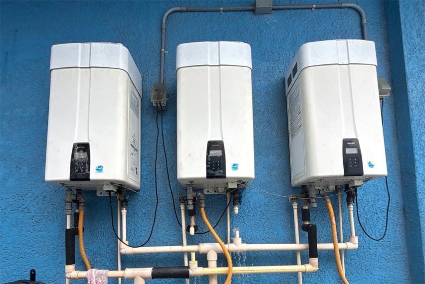 3 Tankless Water Heaters Mounted on a Wall Needing to be Serviced