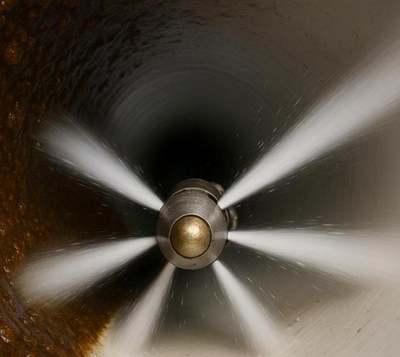View from inside a 4" PVC pipe with a drain jetting nozzle blasting away buildup using high pressure water hydro jetting in Tampa