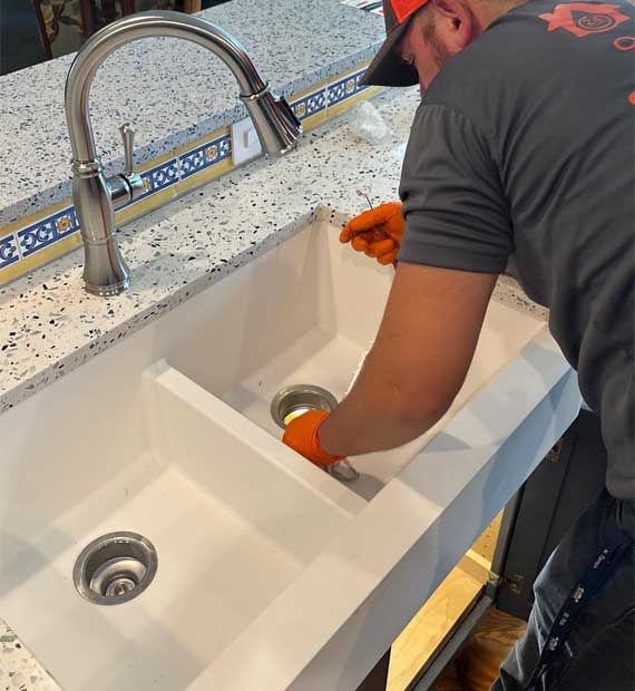 Plumber from All Hours Plumber fixing a kitchen sink drain in a Tampa home