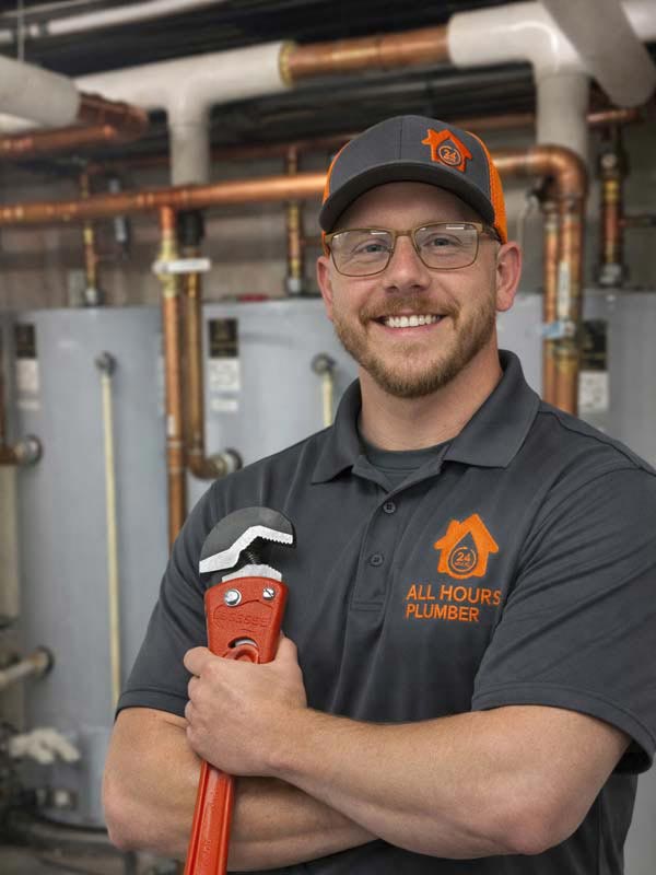 Plumber from All Hours Plumber Standing Holding a Pipe Wrench in Front of Commercial Water Heaters in Maggiano's Restaurant in Westhore Mall