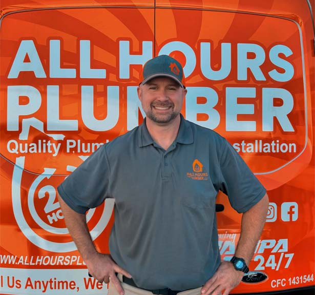 Uniformed Plumber In Front Of An All Hour Plumber Service Van