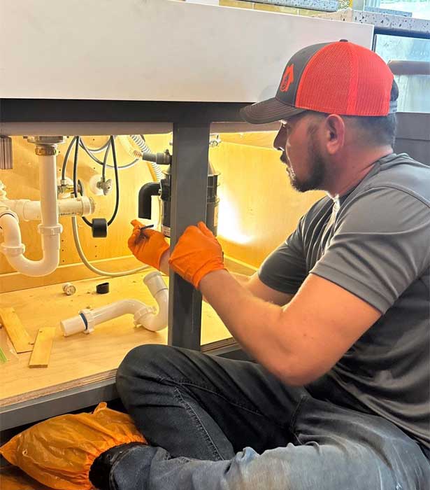 Plumber from All Hours Plumber fixing a tubular drain assembly under a kitchen sink in Tampa