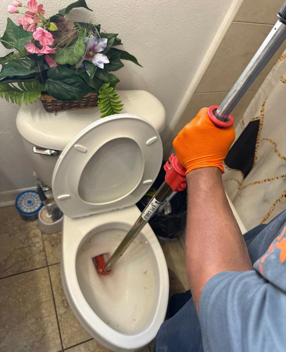 Unclogging a toilet clog with a toilet auger.