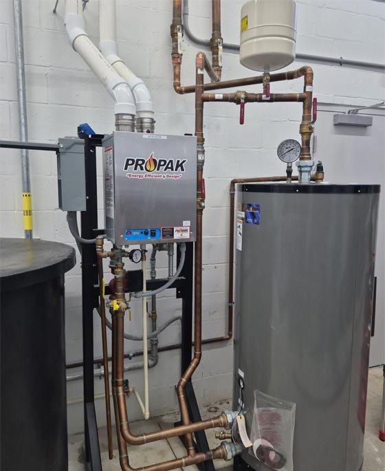 Commercial grade dual tank and tankless gas water heaters in the utility area of a car wash in Tampa bay.